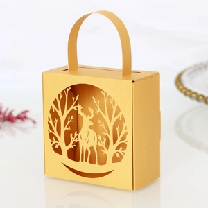 Close-up of laser-cut Christmas reindeer and tree pattern on golden pearl candy gift box