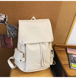 Detail of cream travel backpack with magnetic buckle flap and drawstring closure
