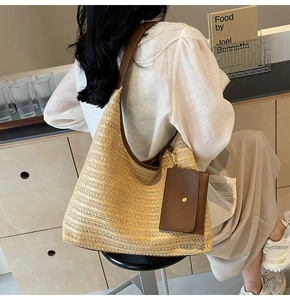 Detail of hand-woven straw bag with brown leather shoulder strap and small pouch