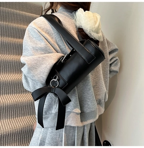 Detail of black cylindrical Boston bag with oversized bow and silver hardware accents
