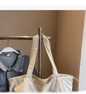 Detail of off-white canvas tote bag featuring adjustable drawstring and long top handles