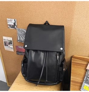 Detail of matte black PU leather backpack with vintage metal buckles and drawstring closure