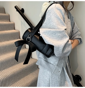 Detail of a black Boston bag featuring a large decorative side bow with silver metal hardware