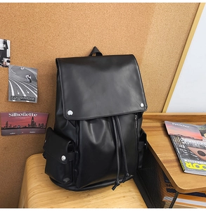Detail of vintage black leather backpack showing magnetic metal buckles and drawstring