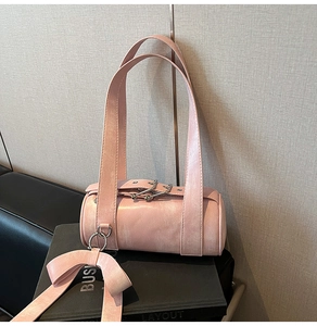 Détail du sac cylindrique rose métallisé avec ruban décoratif en nœud et boucle en métal