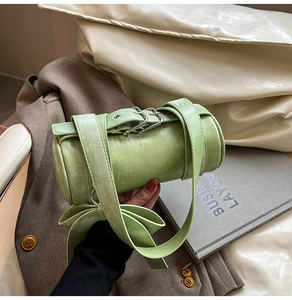 Détail du sac Boston vert avec nœud latéral et lanières à boucles métalliques