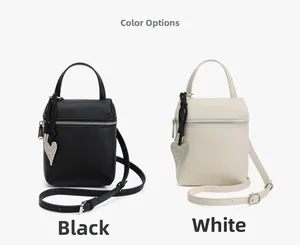 Détail de mini sacs bandoulière en cuir noir et blanc avec breloques en cœur