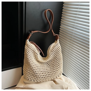 Detail of beige crochet woven tote bag featuring brown leather straps and zipper closure