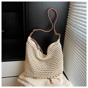 Close-up of woven mesh texture and brown leather strap on a cream straw tote bag