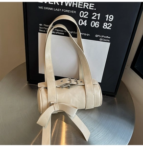 Vue détaillée du sac Boston crème avec boucles métalliques et grand nœud décoratif