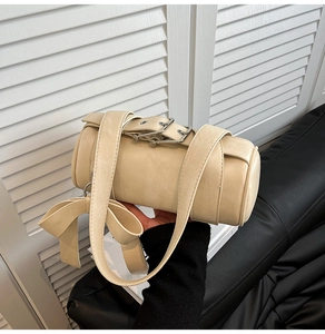 Detail of a beige cylinder bag featuring a large bow and silver buckle strap detail