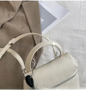 Gros plan du sac en cuir grainé crème avec anneau argenté et cordon de serrage tissé