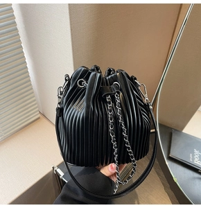 Close-up of black pleated bucket bag with silver metal chain and vertical pleats detail