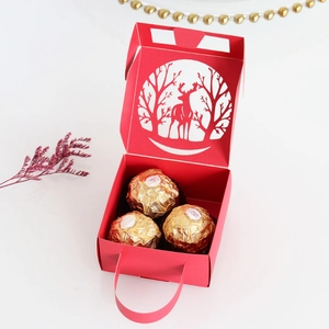 Close-up of red laser-cut Christmas gift box with reindeer patterns and handle