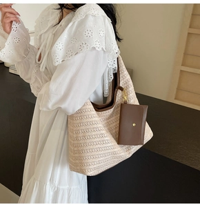 Detail of hand-woven straw tote bag with brown leather handles and small hanging purse