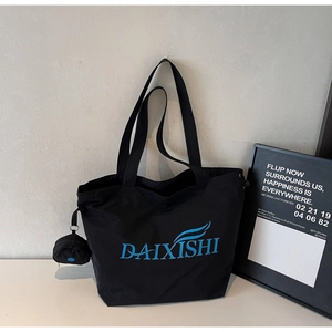 Detail of a black large-capacity tote bag featuring a blue logo and small round coin purse