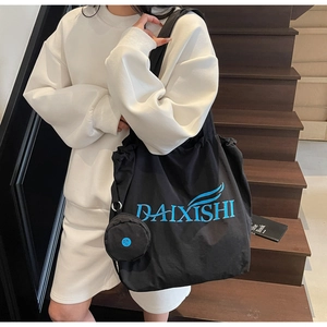 Detail of a large black tote bag with blue logo and small round zippered pouch on a strap