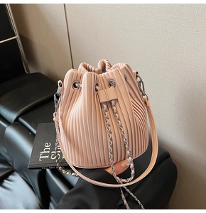 Detailed view of the pale pink pleated bucket bag with silver chain and drawstring closure
