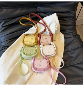 Group display of mini leather saddle bags in five pastel colors with cartoon bear detail
