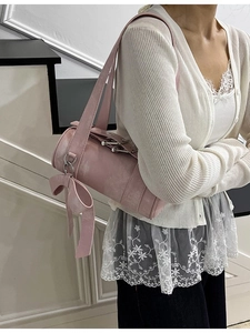 Sac Boston cylindrique rose avec grand nœud sur la bandoulière porté par un mannequin