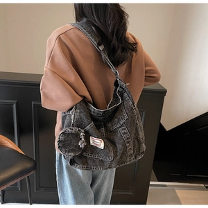 Detail of washed denim shoulder bag featuring a detachable round coin purse and white label