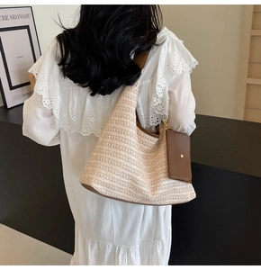 Detail of woven straw tote bag with brown leather trim and hanging mini pouch