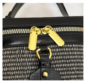 Detailed close-up of premium gold-tone metal dual zippers on a black textured handbag