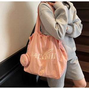 Side view of a large pink tote bag with matching coin purse on a shoulder of a person