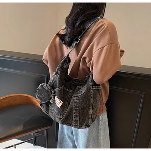Detail view of washed denim hobo bag with side pockets and a detachable small round coin pouch