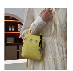 Détail du sac bandoulière en cuir jaune avec pendentif coeur et fermeture éclair argentée