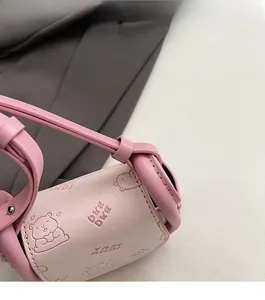 Close-up of pink cylindrical bag showing fine stitching and cute bear pattern detail