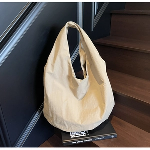 Dettaglio di una borsa tote in nylon beige su un libro per un look moderno in stile urbano
