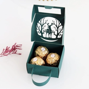 Macro shot of forest and elk laser cutouts on a dark green paper gift box