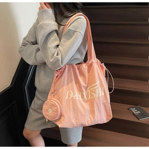 Detail view of large pink tote bag with brand logo and matching zipper pouch charm