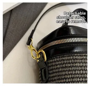 Detail of the detachable black leather strap with gold buckle on a woven box bag