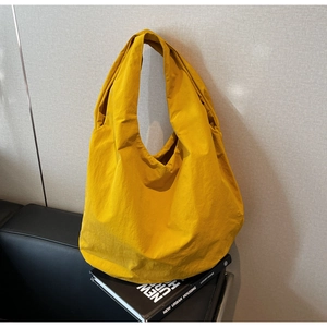 Dettaglio di una borsa tote in nylon giallo con trama lavata e ampi spallacci comodi