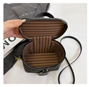 Top view of compact black leather box bag showing striped fabric lining and inner storage