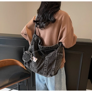 Detailed view of a black denim tote bag with external pockets and a small round pouch