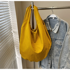 Dettaglio di una grande borsa tote in nylon giallo senape appesa per il pendolarismo