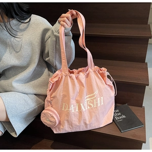 Detailed shot of pink drawstring tote bag featuring a logo and round coin purse accessory