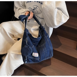Detail of blue denim tote bag featuring white contrast stitching and a small round coin purse