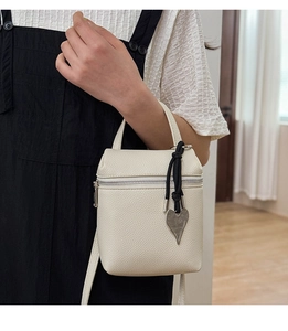 Detail of off-white lychee pattern leather mini crossbody bag with heart pendant