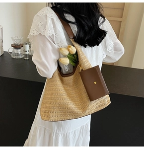 Detail of hand-woven straw tote with brown leather strap and small pouch accessory