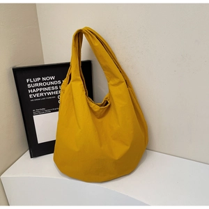 Dettaglio della trama in nylon giallo con pieghe naturali e tracolla larga della borsa