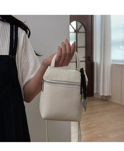 Close-up of white lychee pattern leather bag with silver zipper and heart charm detail