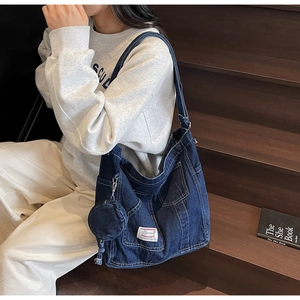 Detail of deep blue denim tote bag with external pockets and a mini round pouch pendant