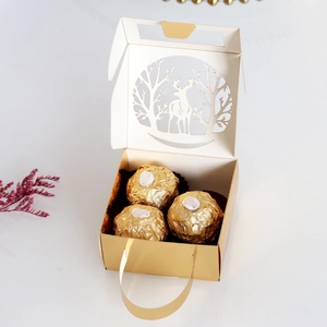 Detail view of golden laser-cut Christmas gift box with elk forest pattern and handle