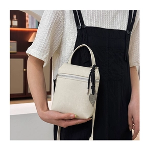 Détail du sac à main en cuir blanc cassé avec pendentif cœur et tirette en corde tressée
