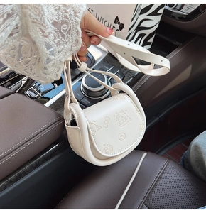 Close-up of cream crossbody saddle bag with cute embossed bear and bow patterns