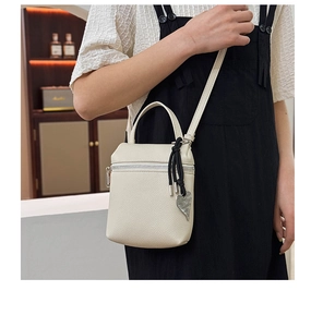 Detail of off-white lychee texture leather mini crossbody bag with heart pendant detail